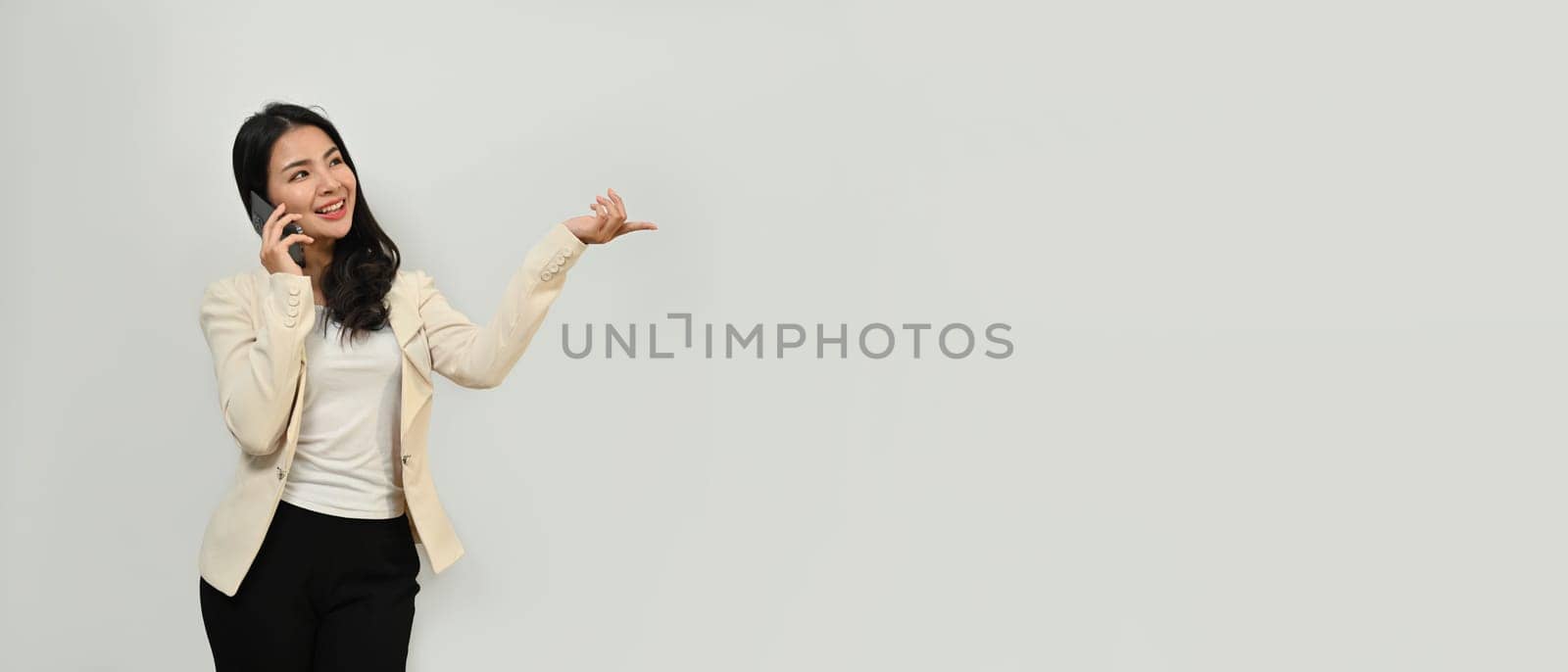 Portrait of satisfied business influencer woman talking on mobile phone isolated over white background.