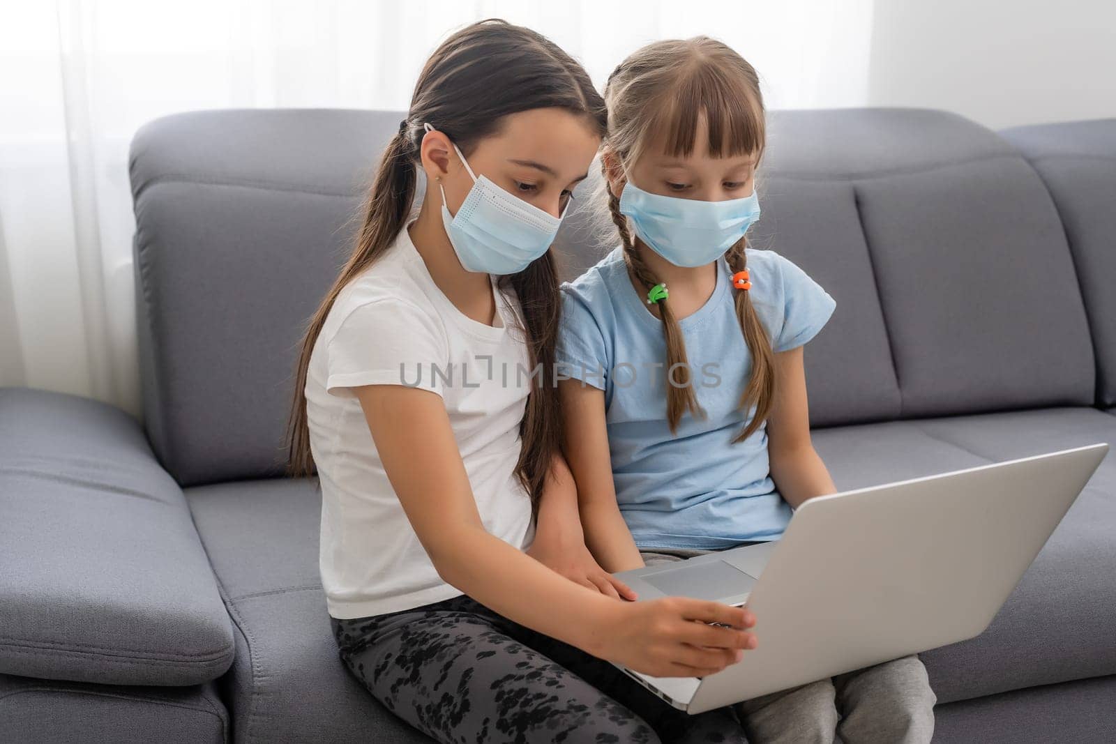 School little girls studying at home wearing mask, distant learning.