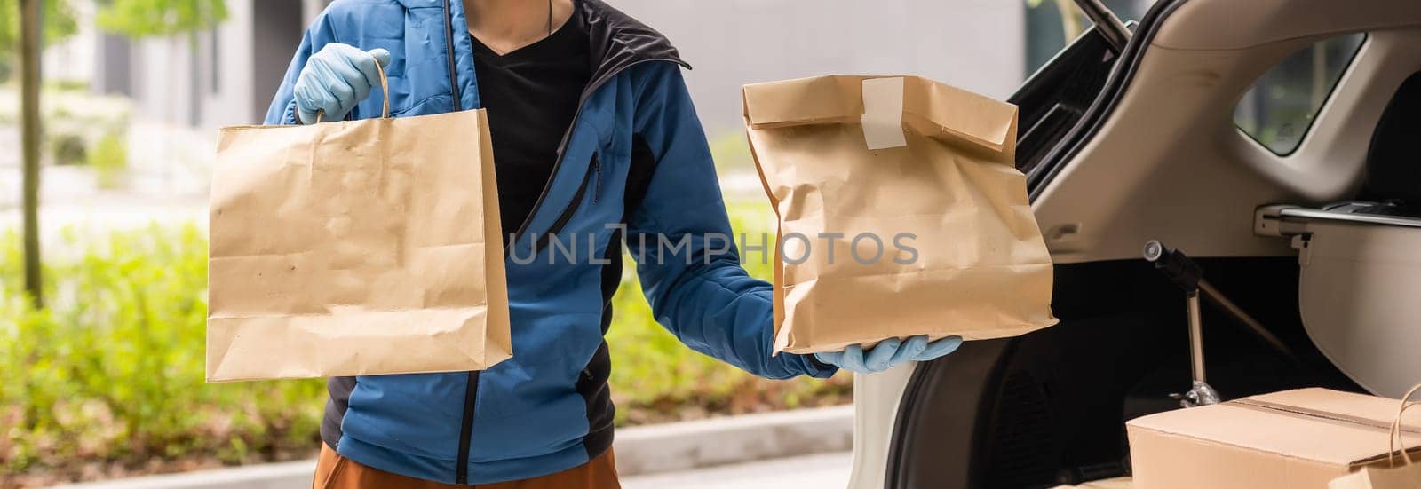 Postal delivery courier man wearing protective face mask in front of cargo van delivering package holding box due to Coronavirus disease or COVID-19.