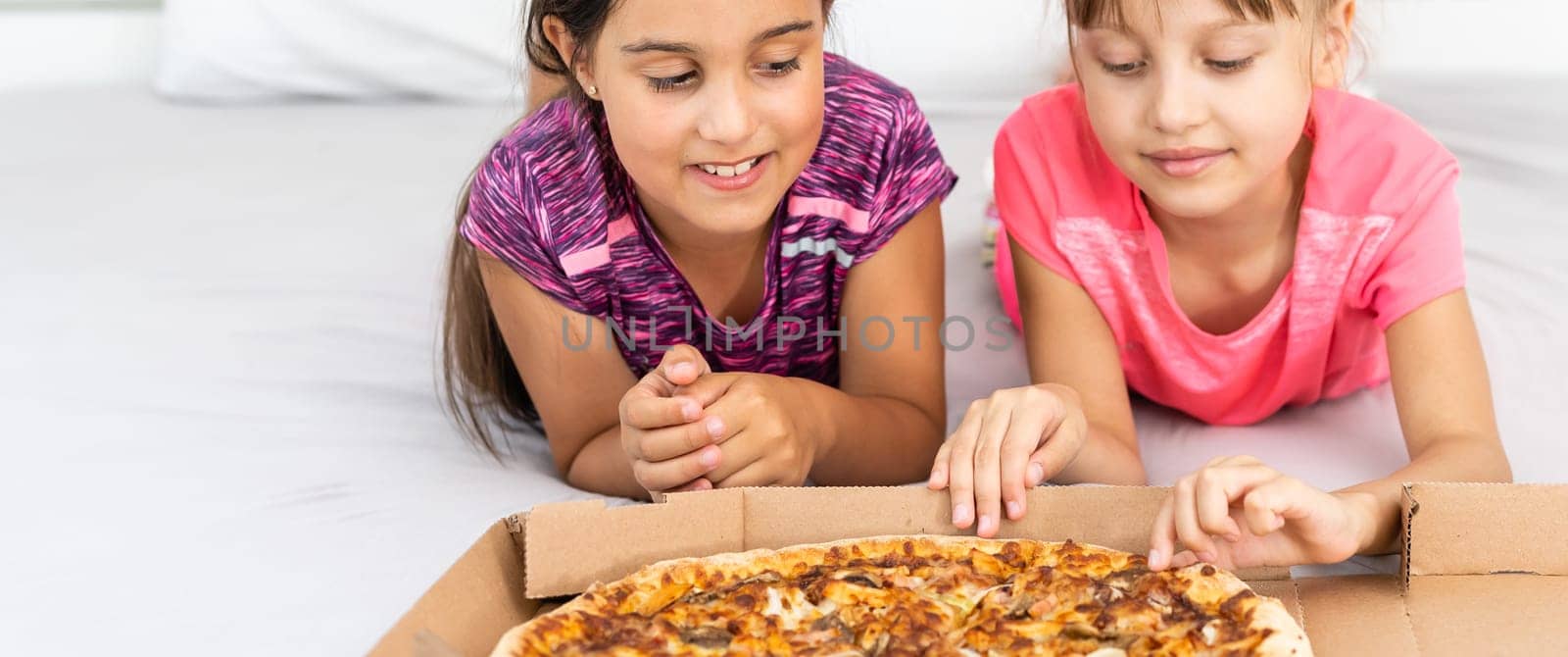 Two little girls eating pizza at home by Andelov13