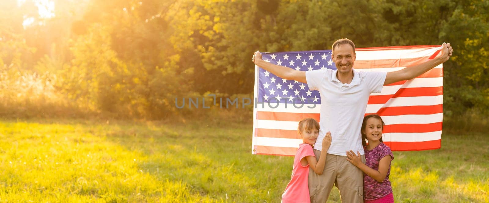 parents and child with American flag are playing with a colorful kite. mother, father and their little daughters celebrate together 4th of July outdoors in foggy day. Independence Day of USA concept