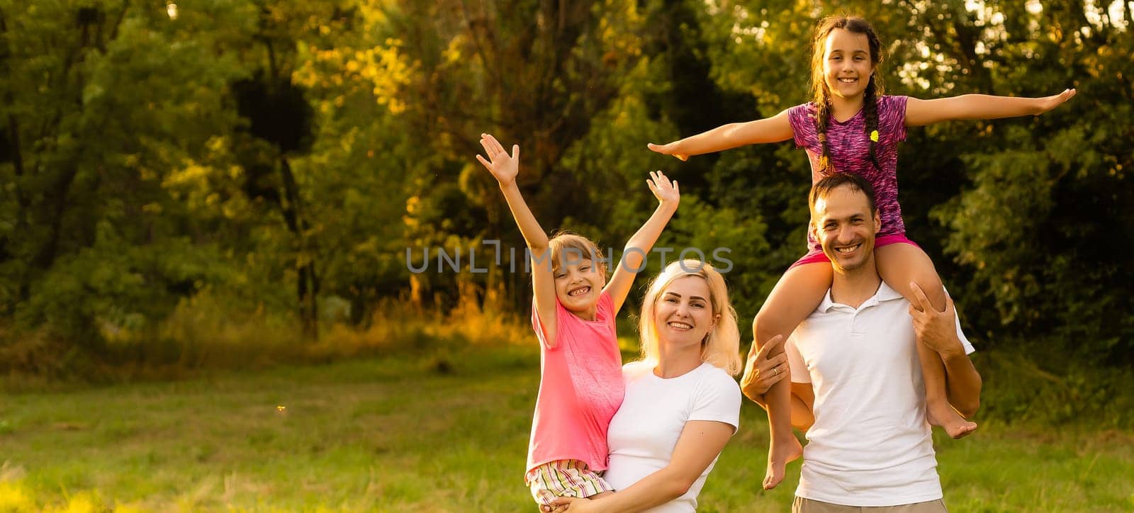 Happy family walking in field and looking at sunset.