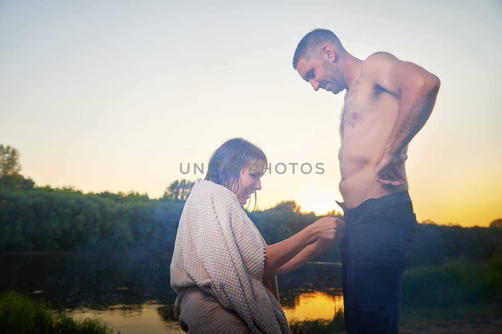 Happy Couple Outdoor relaxin and having fun on nature in the park in summer evening with smog and fog. Family or lovers have date and rest outdoors. Girl takes off jeans from man or guy