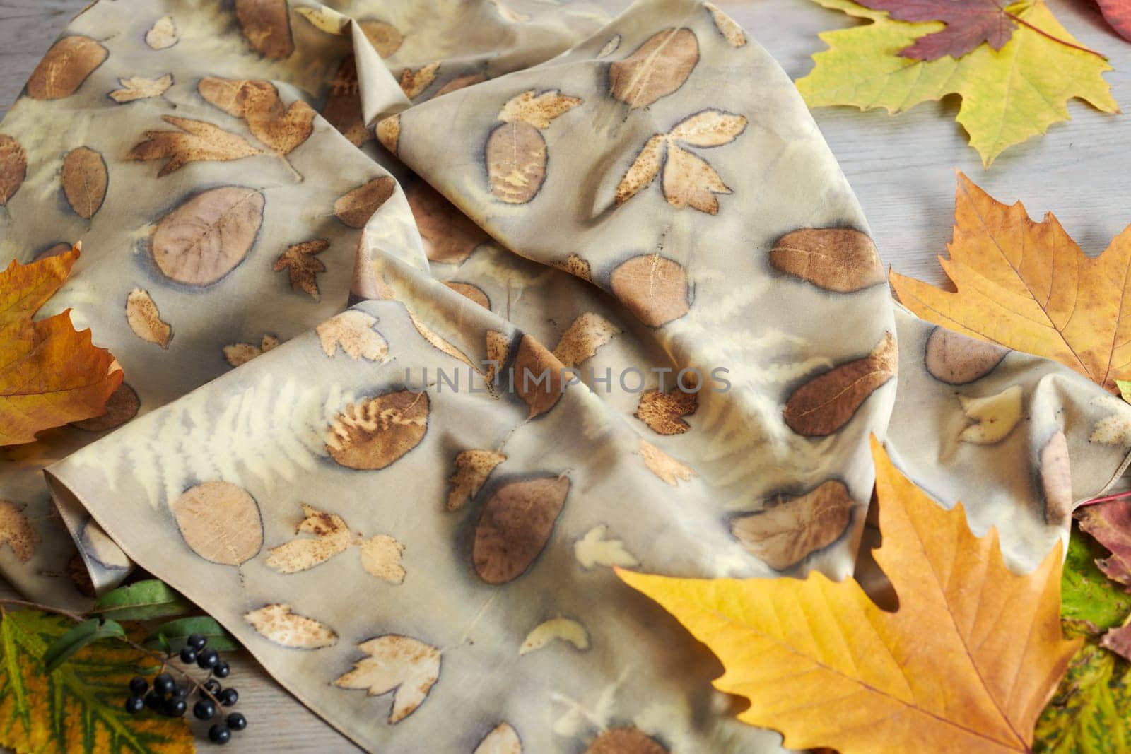 Hand-dyed silk scarf surrounded by autumn leaves. Eco-print technique by maxcab