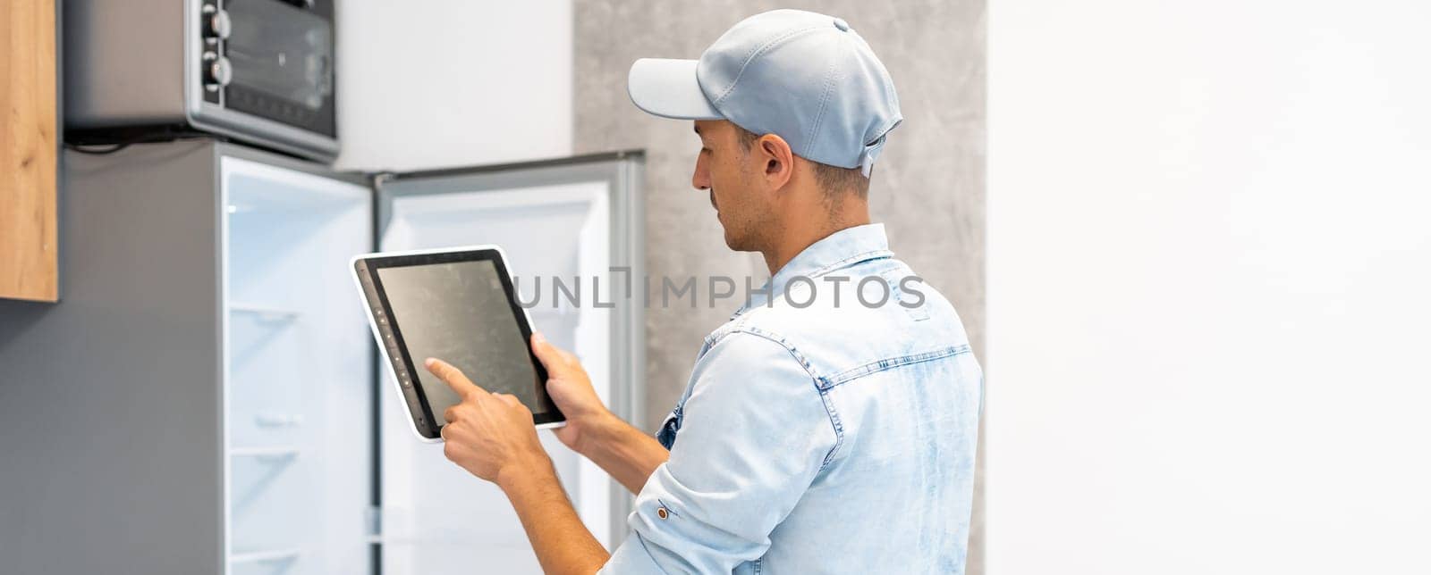 Male worker types on a tablet, kitchen renovation.