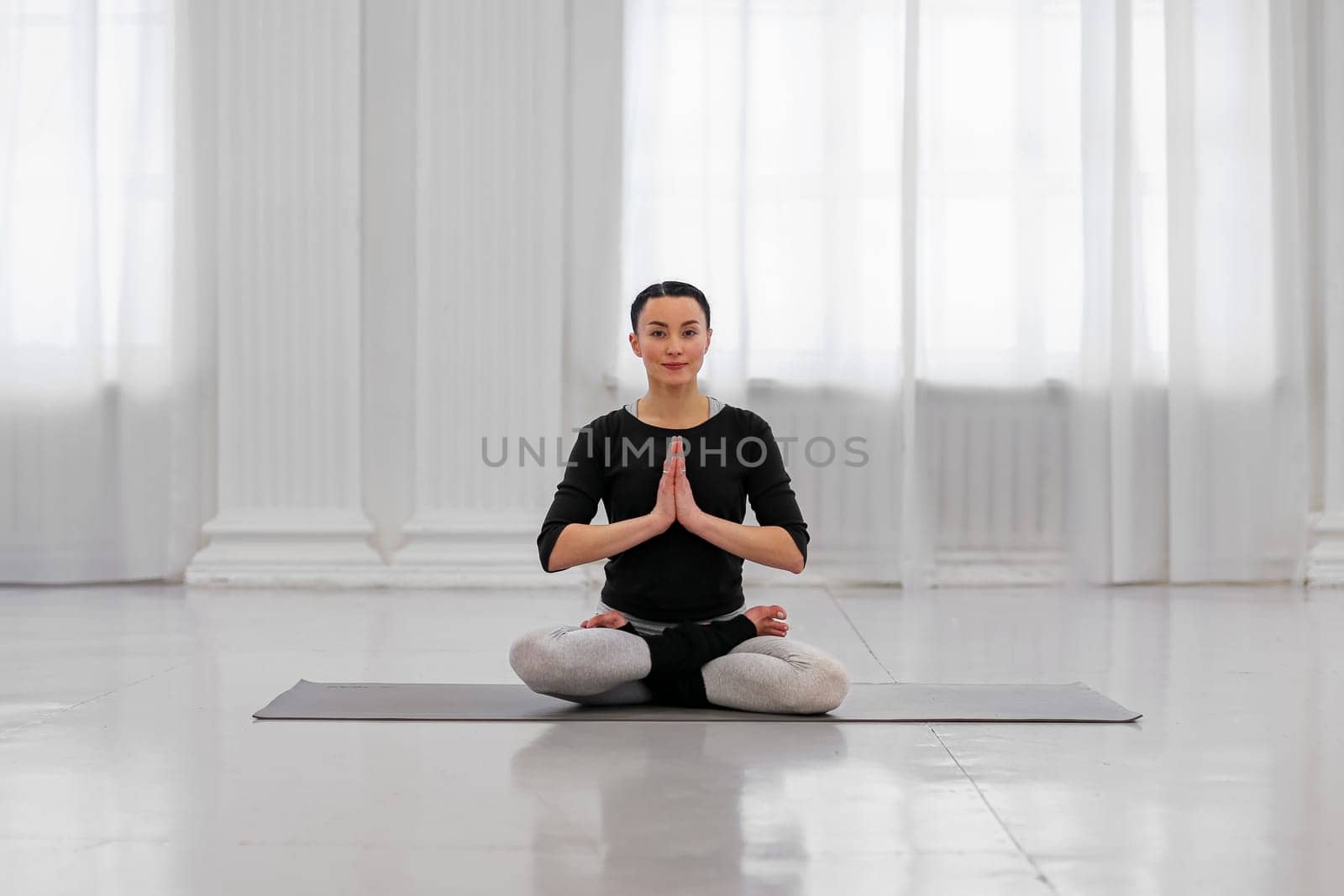 Healthy young woman doing padmasana lotus pose during yoga classes in a cozy bright room. The concept symbolizes purity and perfection with Buddhist meditation.