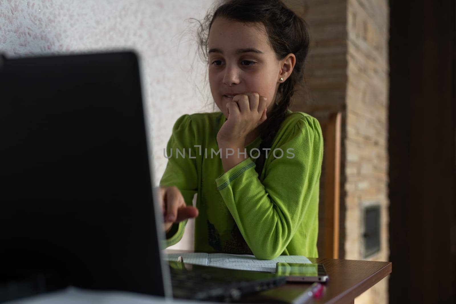 Smiling little Caucasian girl in headphones have video call distant class with teacher using laptop, happy small child wave greeting with tutor, study online on computer, homeschooling concept by Andelov13