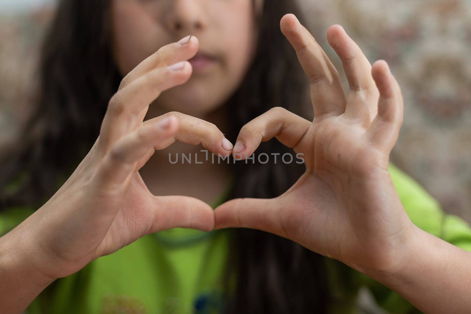 Photo of casual cheerful cute funny girl showing heart shape sign with fingers above her head.