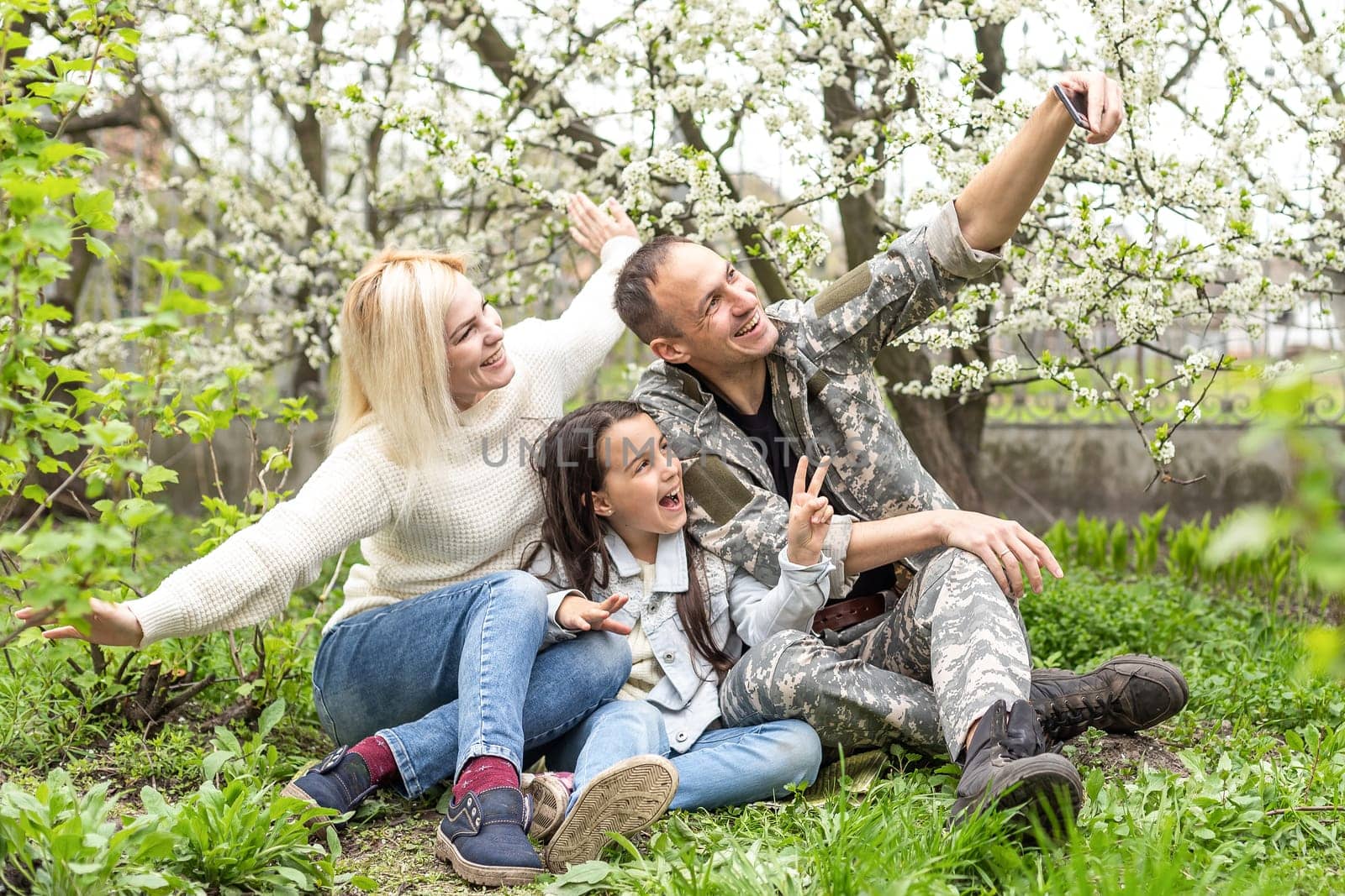 Soldier is meeting his family outdoors. Happy reunion of father and kids on the grass.