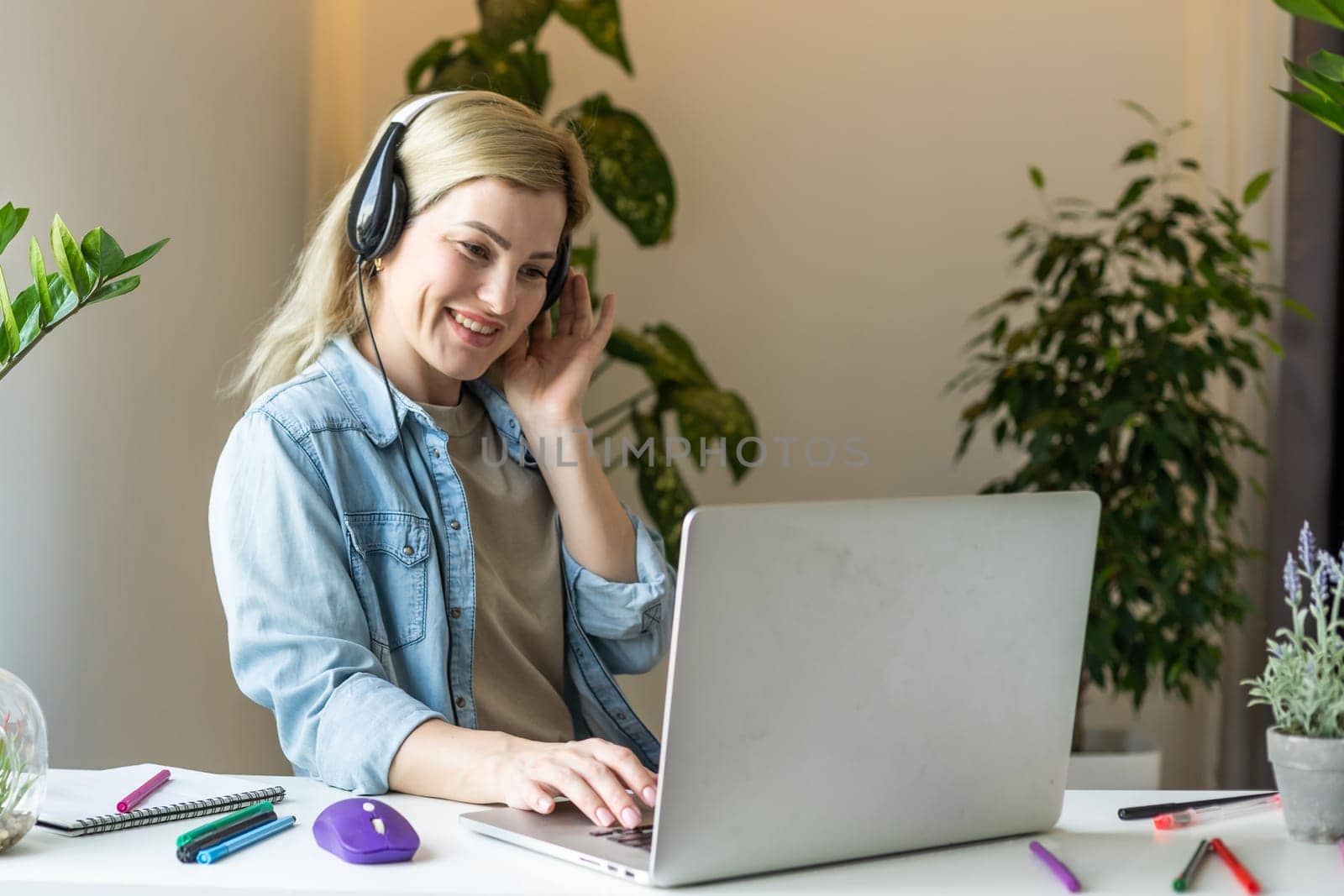 Meeting online. Young woman wearing headphones using laptop watching webinar or doing video chat by webcam. Business conference. E-learning education concept.