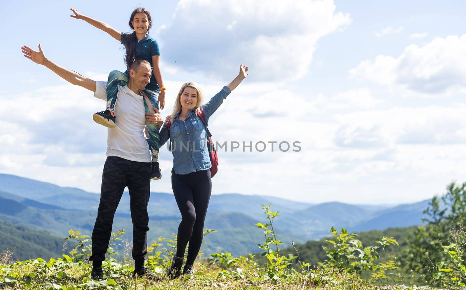 Family hiking parents with child outdoor travel in mountains active vacations lifestyle mother and father backpacking together