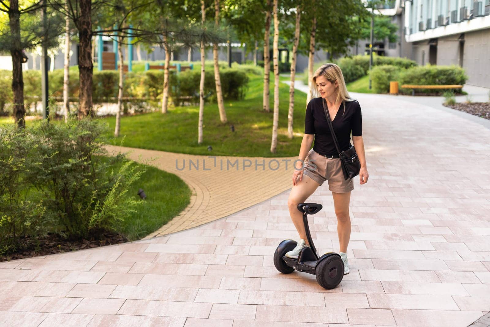 woman riding electric mini segway hover board scooter in green park. Good summer weather, ecological urban transportation technology and pretty model.Electric self-balancing scooter board.
