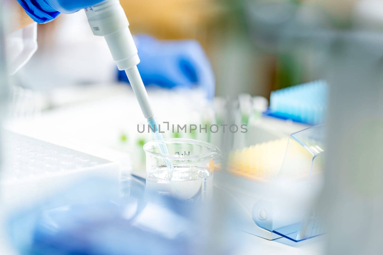 conducting chemical research in a research laboratory. pipetting the sample into glass flasks by Edophoto