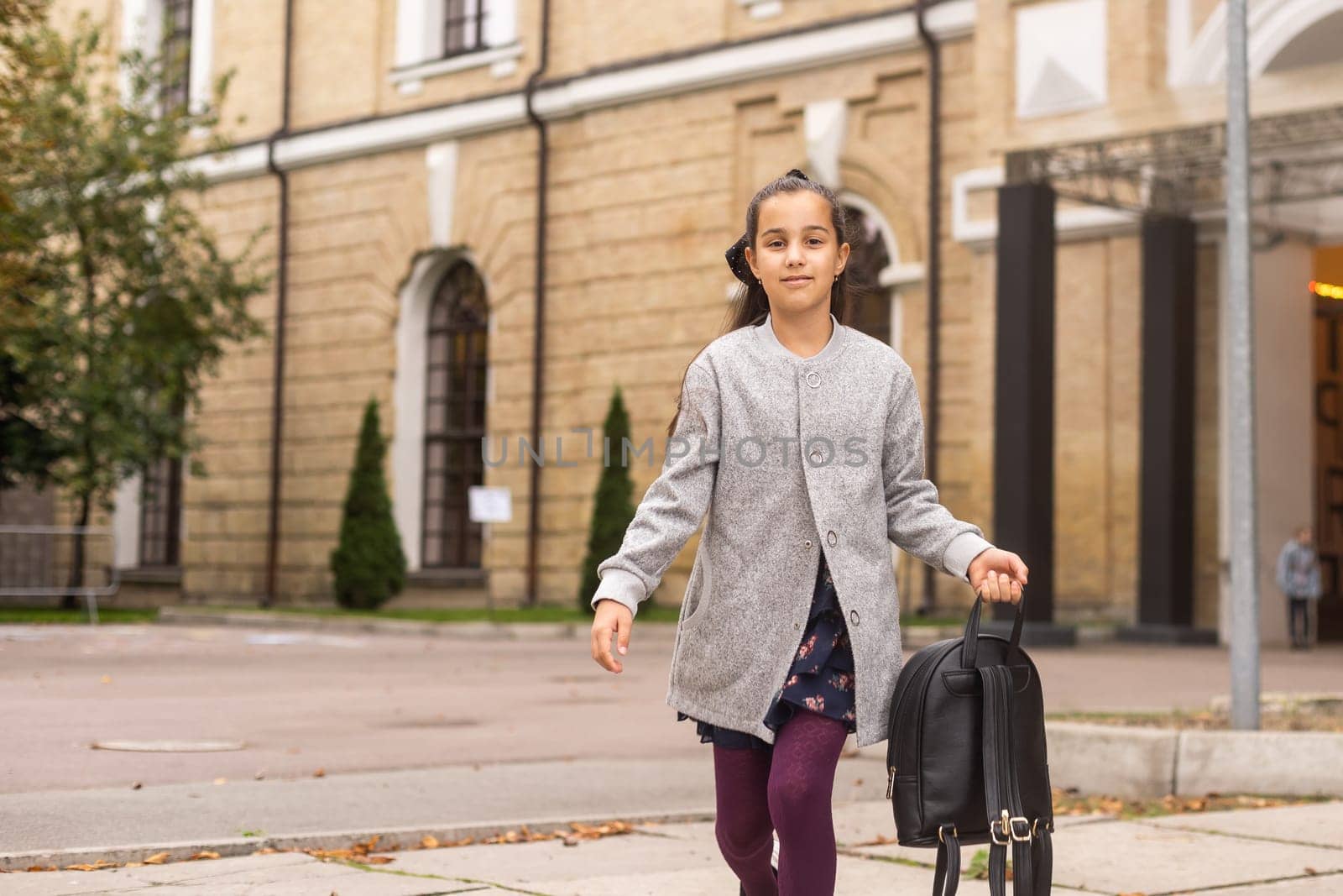 Cute young girl with a backpack heading to school on cold autumn morning