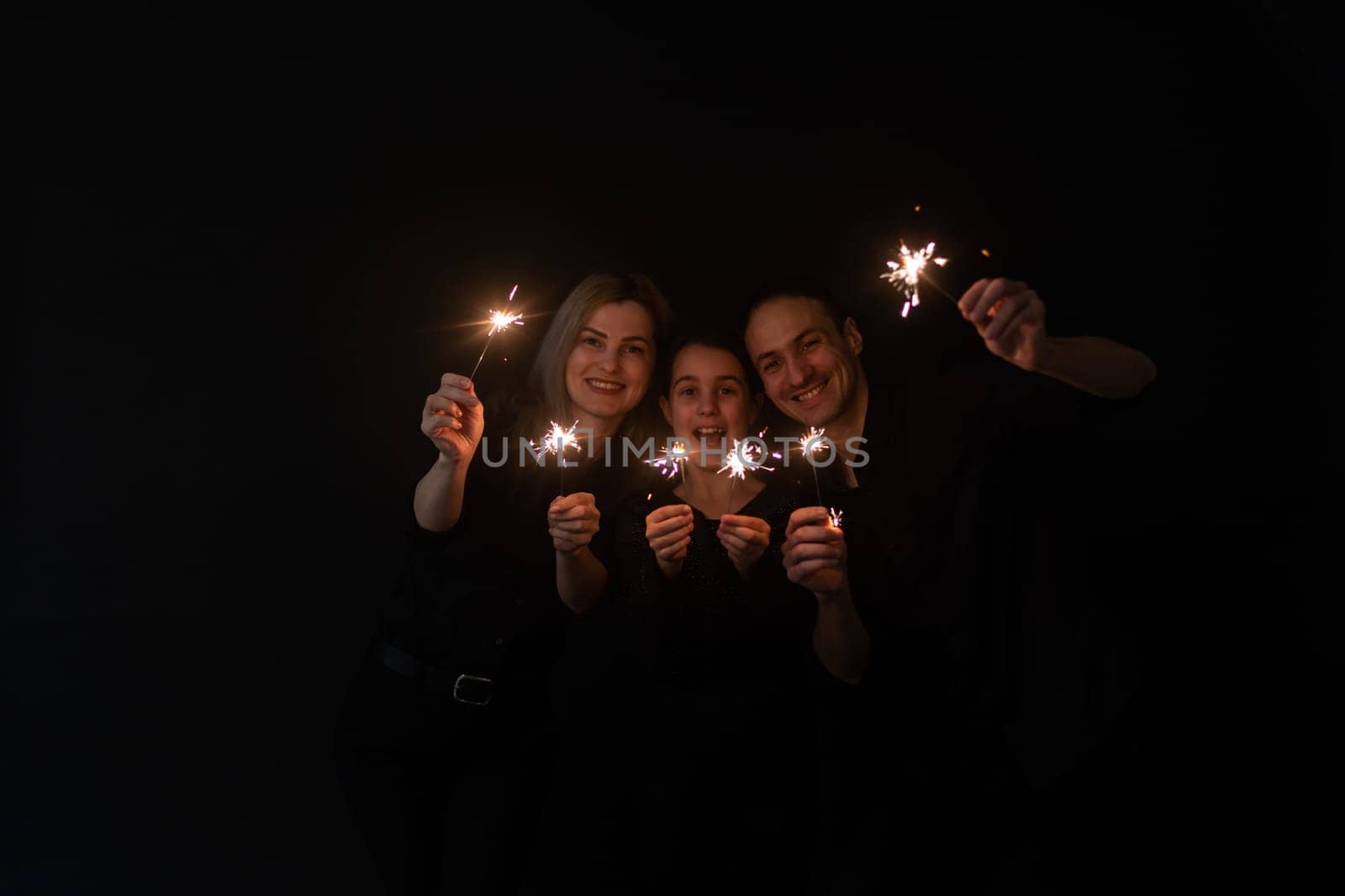 Beautiful family celebrating Christmas and holding sparklers.