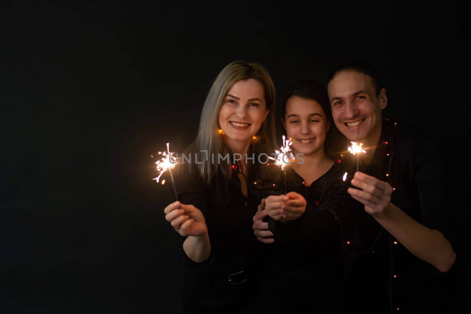 Beautiful family celebrating Christmas and holding sparklers.