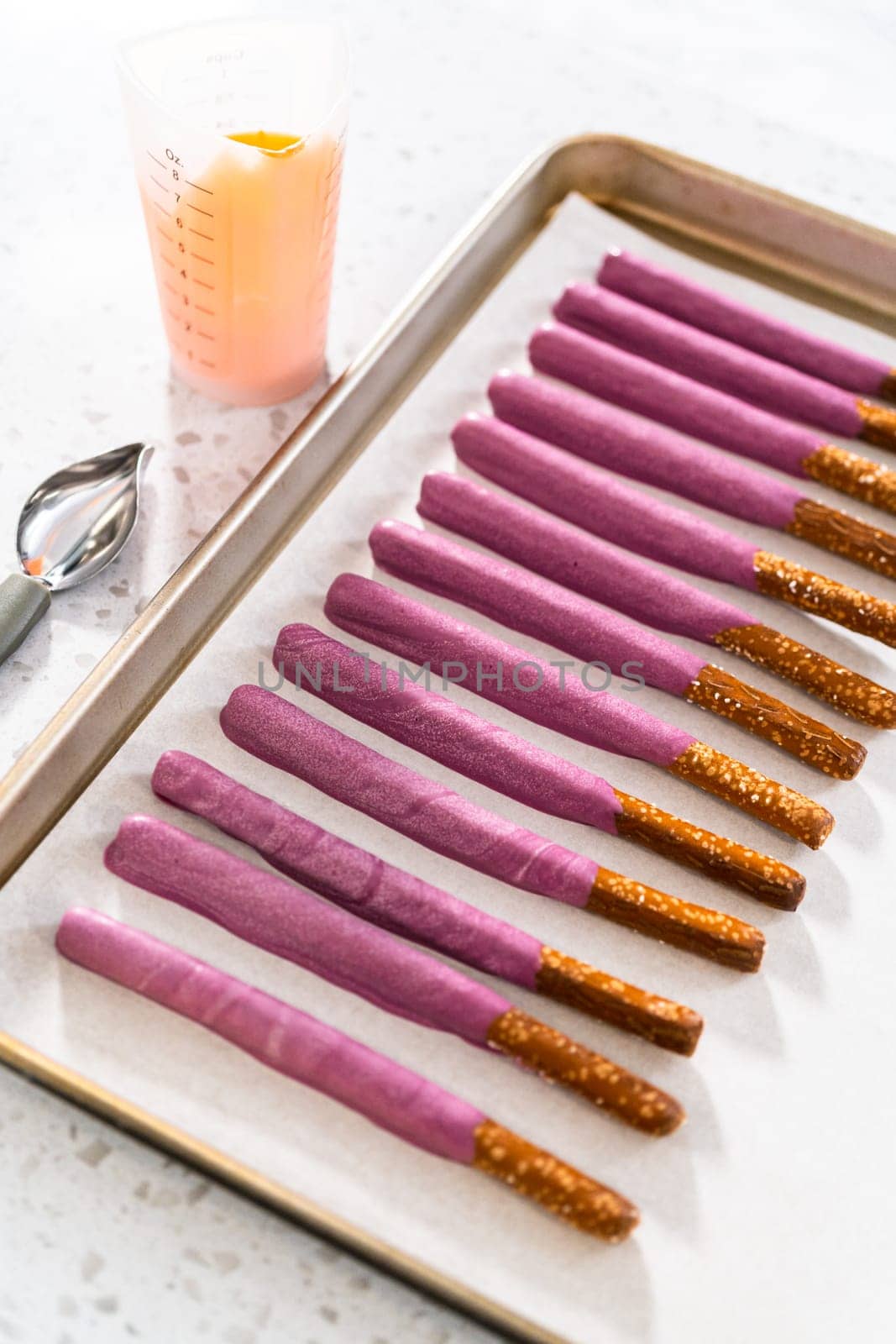 Dipping pretzel rods into melted chocolate to make Halloween chocolate-covered pretzel rods.