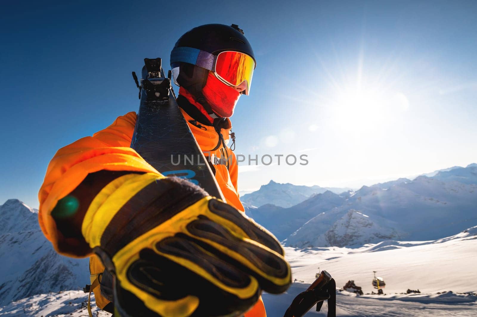Close-up portrait of a guy holding skis in winter, he is wearing sportswear such as a helmet and sunglasses. winter, freedom, nature, sports, competitions. winter holidays in the alps, travel, hiking by yanik88
