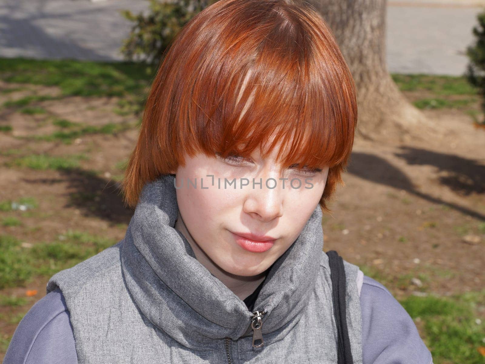 portrait of a smiling red-haired teenage girl in sunlight.