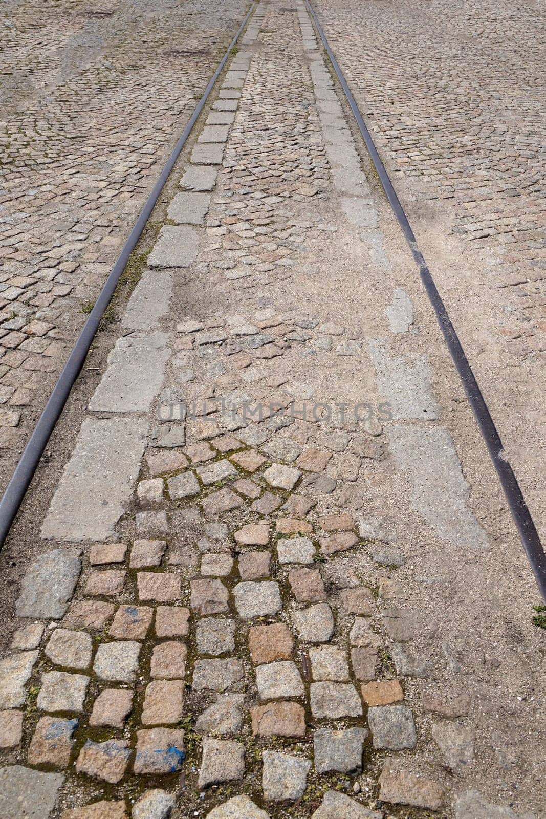 old rails in pavement stone paving for vertical vintage background.