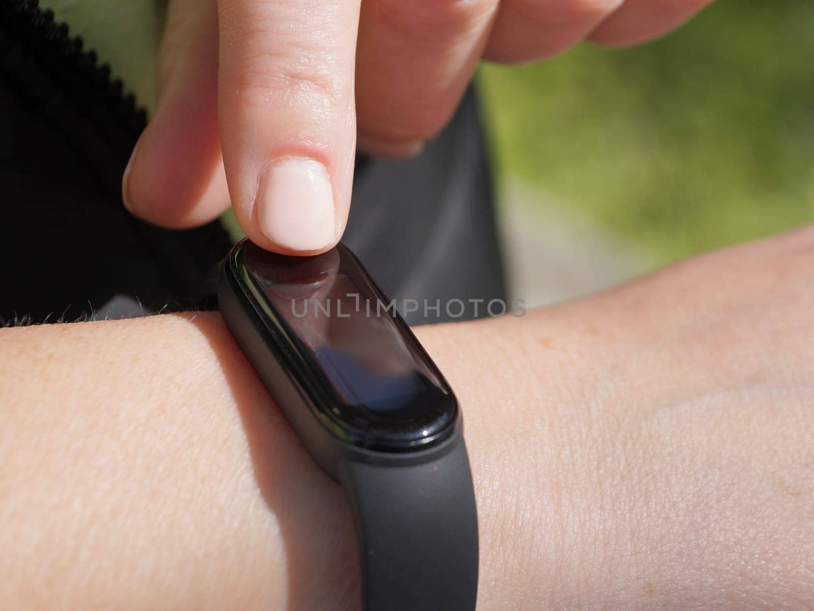 Using a fitness bracelet, a woman measures her pulse on the display of a fitness bracelet close-up