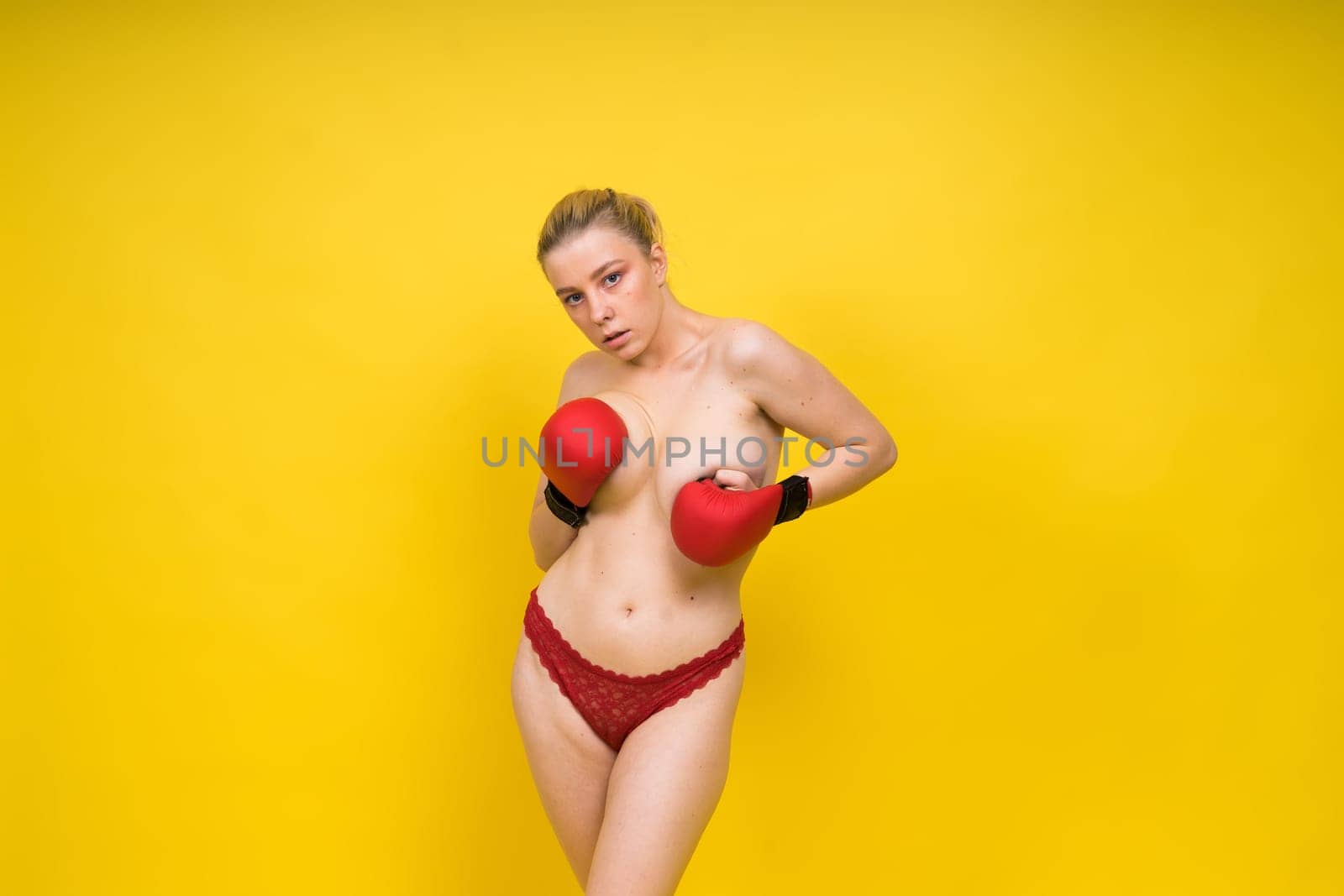 Seductive young and fit female fighter posing in gloves in a studio