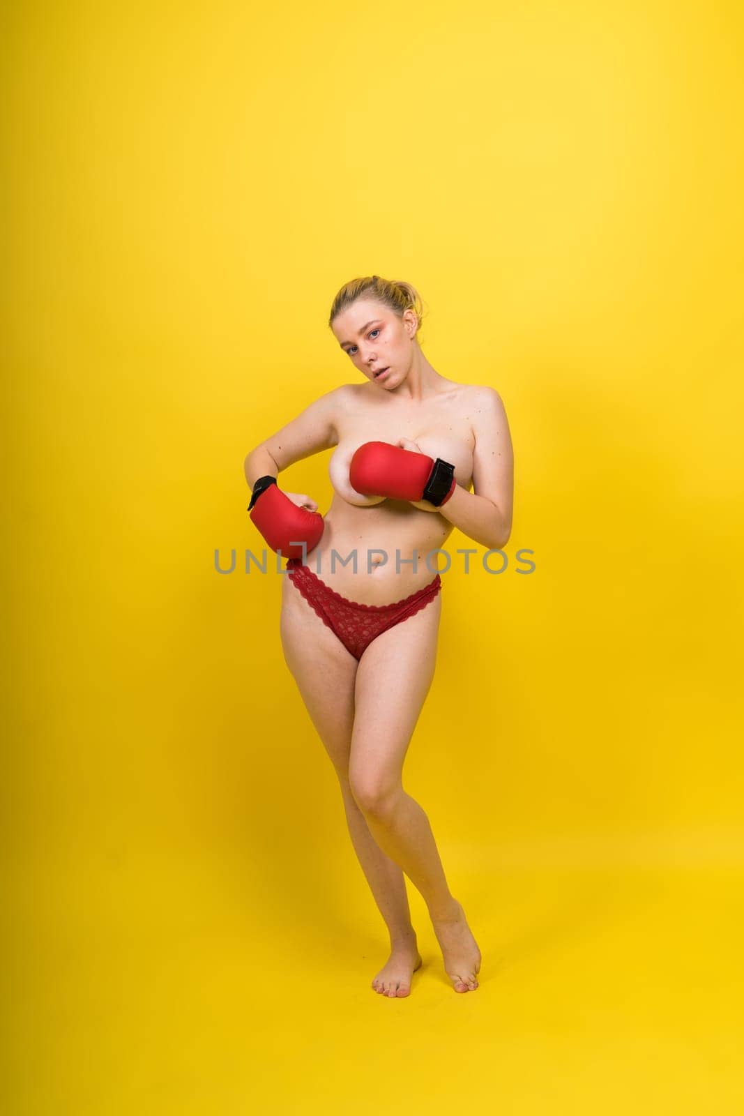 Seductive young and fit female fighter posing in gloves in a studio