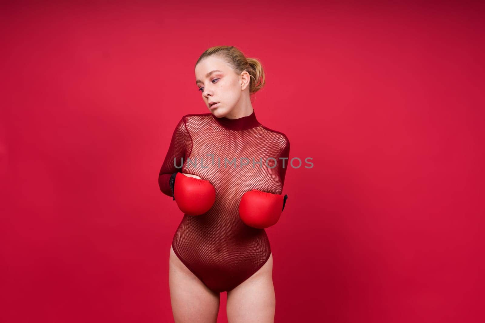 Seductive young and fit female fighter posing in gloves in a studio