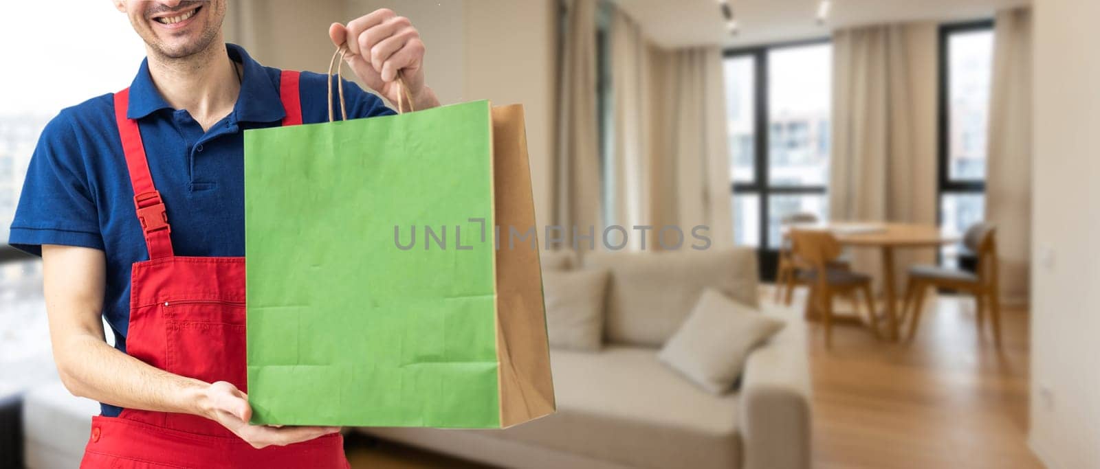 Paper pocket and food containers in hands of a smiling deliveryman. .Quality service of a restaurant