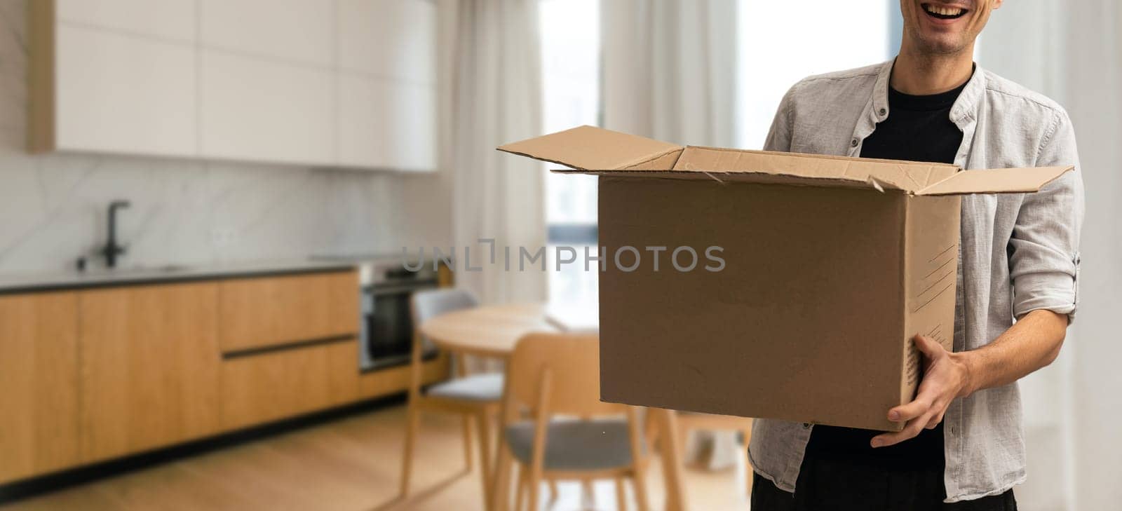 enthusiastic young man carrying cardboard box, moving out of home.