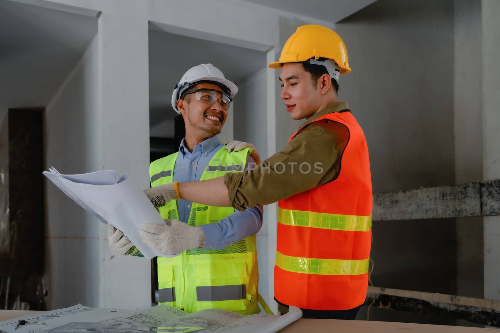 multi ethnic engineer brainstorming and measuring for cost estimating on blueprint and floor plan drawings about design architectural and engineering for houses and buildings.