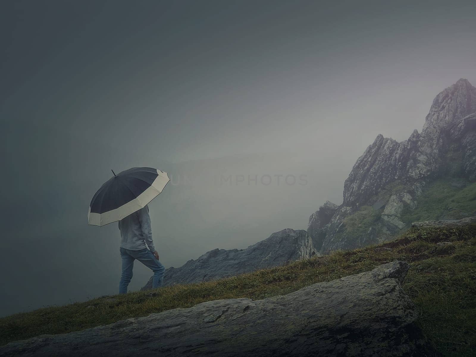 Lone person under umbrella in the foggy mountains