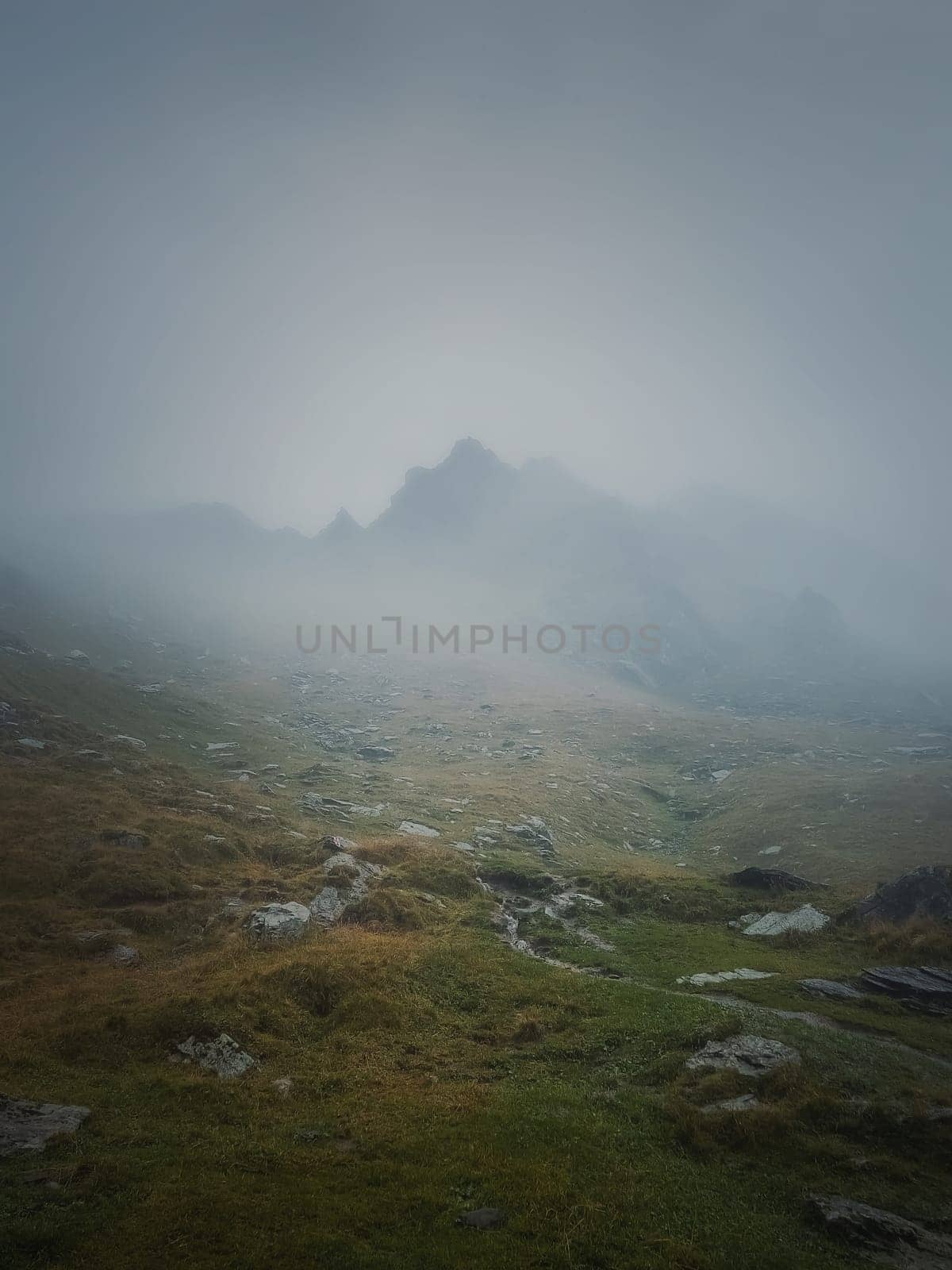 Transfagarasan mountain peak seen through the dense fog. Rainy scene in the mounts, hiking in the mist by psychoshadow