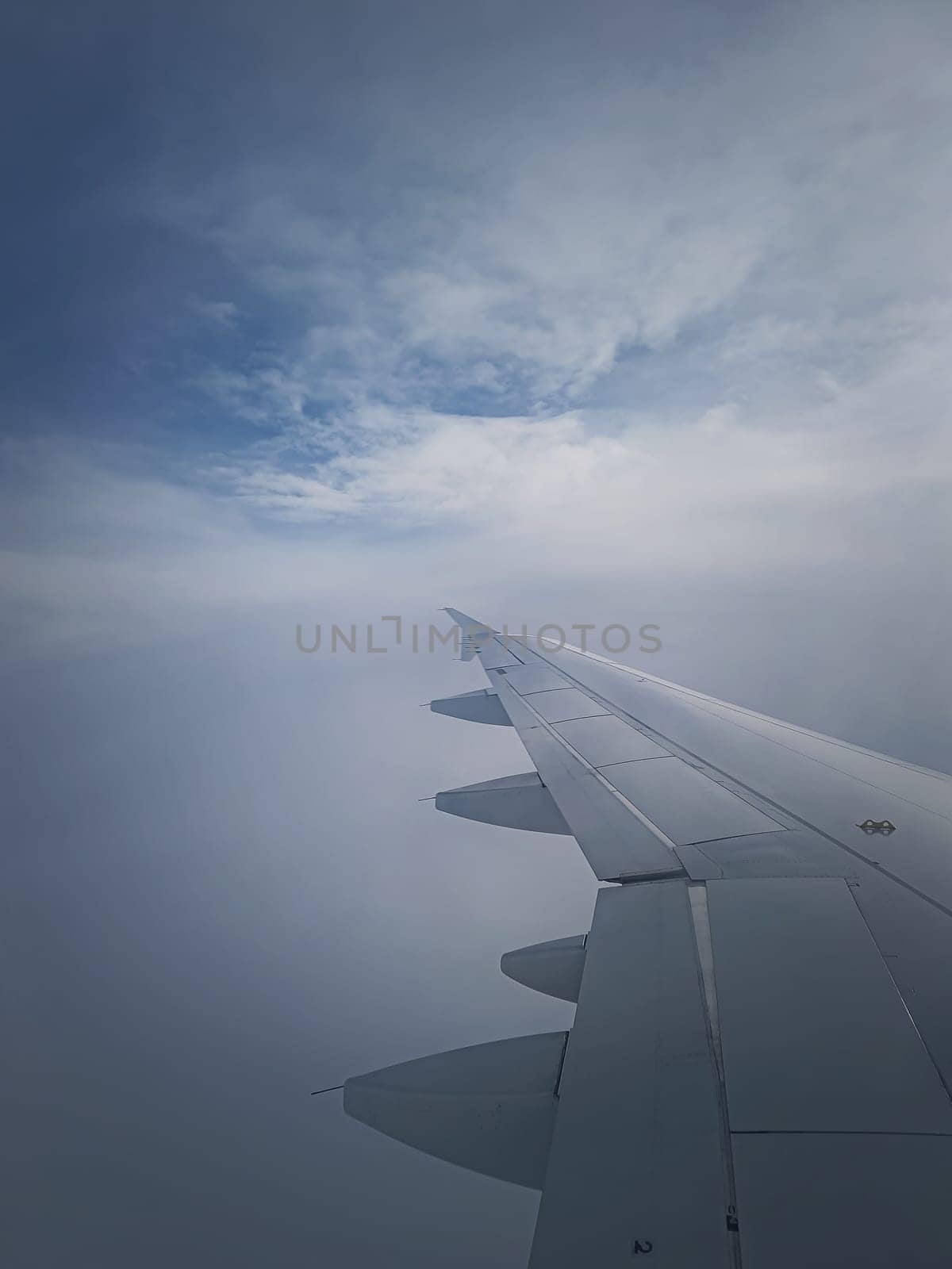 Plane flight through the dense foggy clouds, vertical shot. Airplane wing seen through the window by psychoshadow