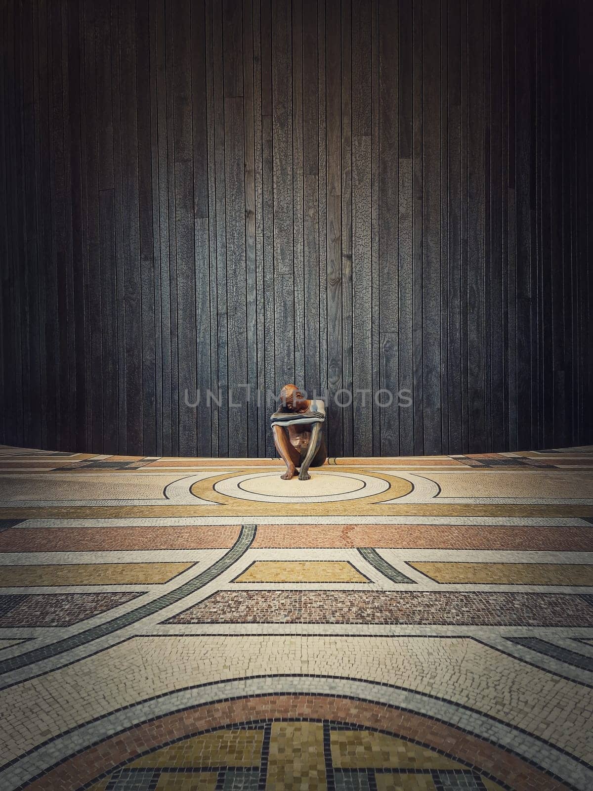 Paris, France, 18 November 2022. Nude by Ugo Rondinone an Exposition inside of the Petit Palais. Lone human statue as a seated man on the floor against wooden wall background