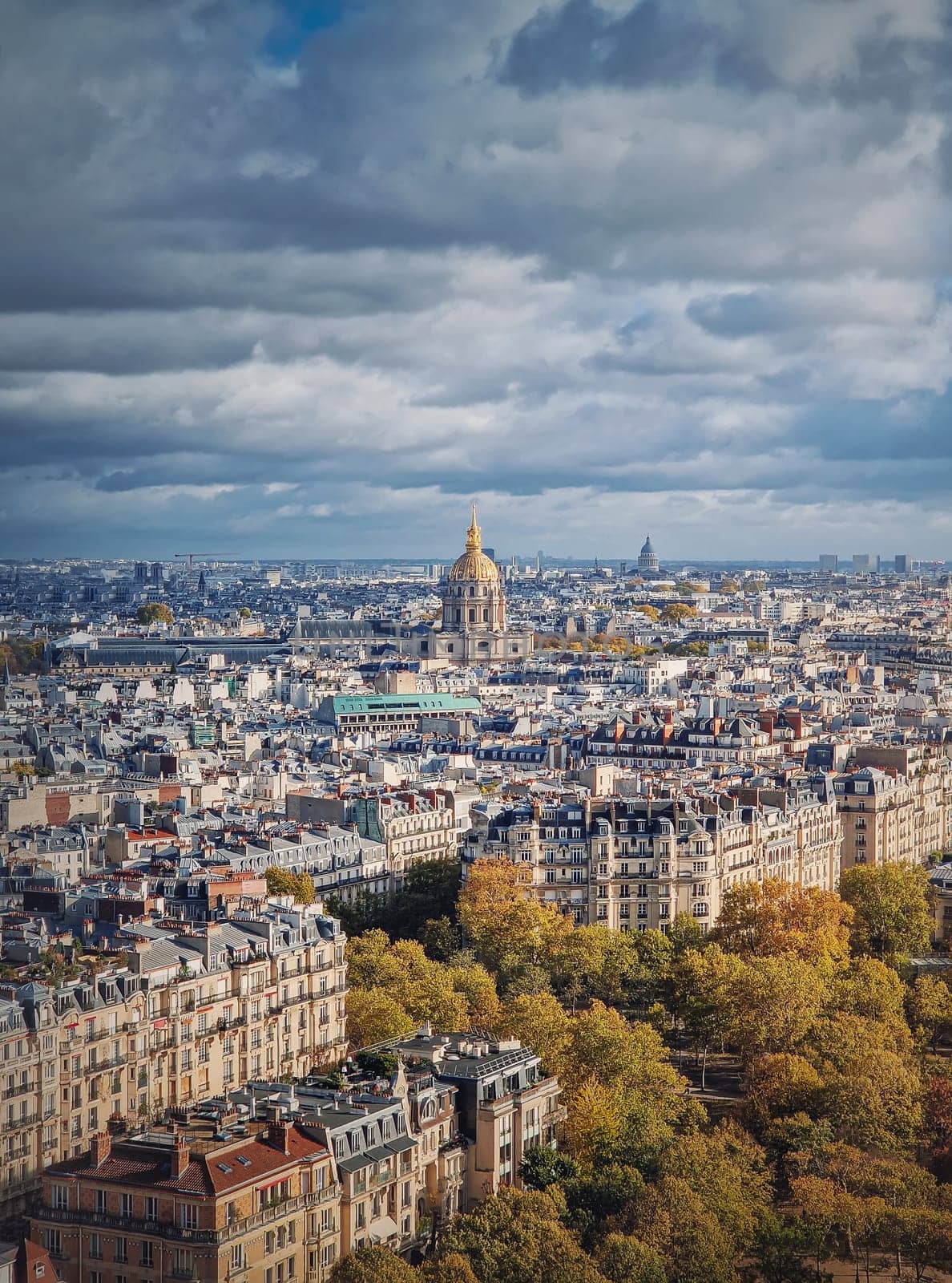 Scenery aerial view from the Eiffel tower height over the Paris city, France. Les Invalides building with golden dome seen on the horizon. Autumn parisian cityscape