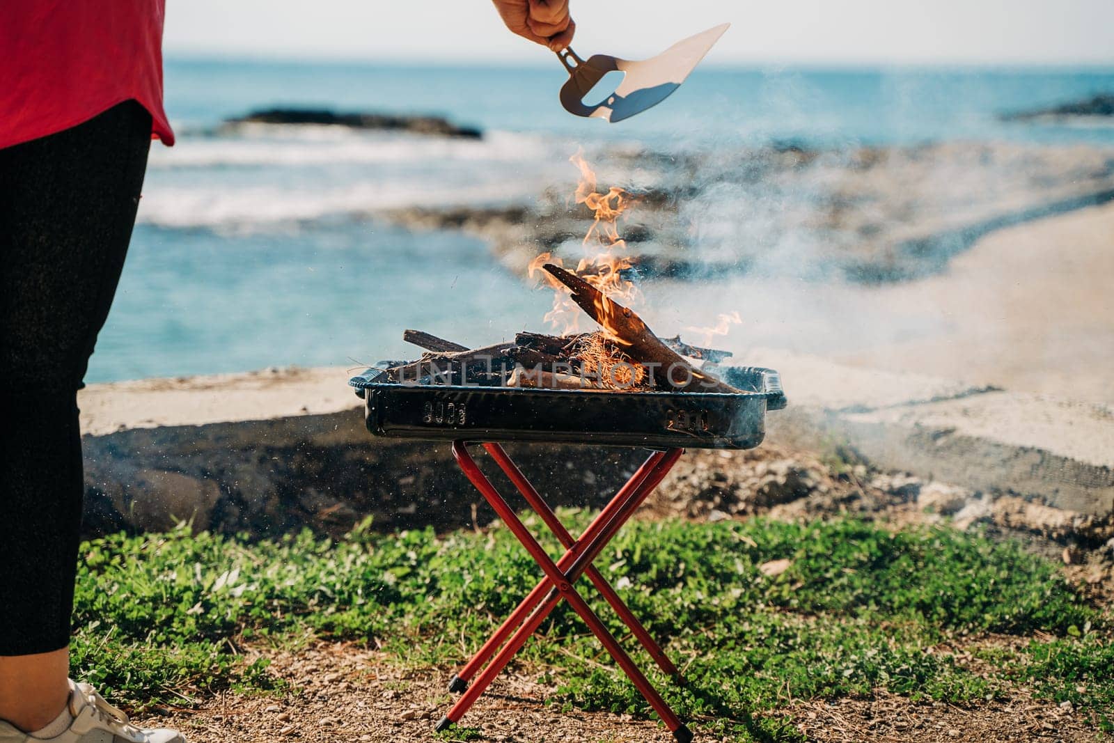 Woman making Barbecue grill in nature forest camping park with sea on background.