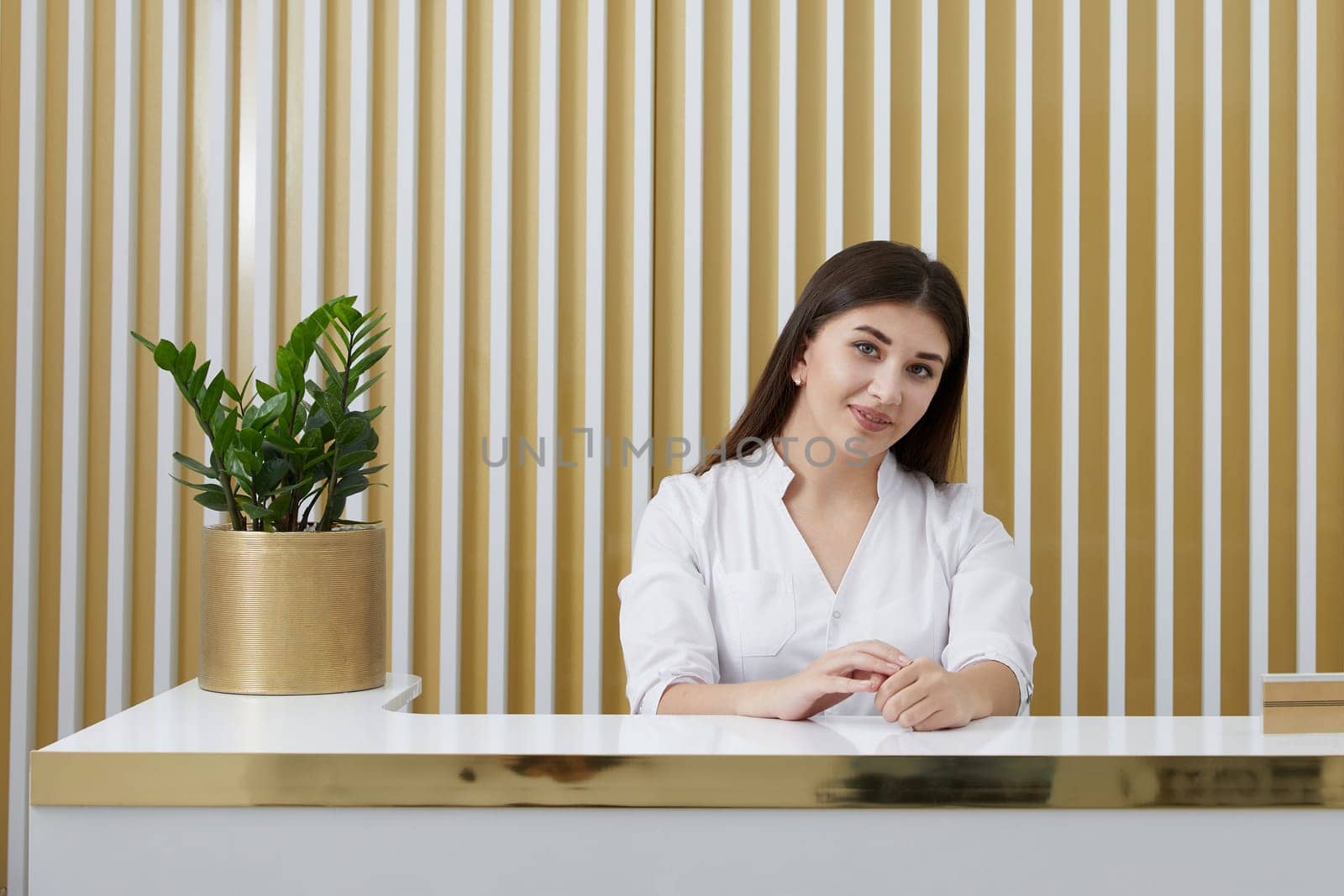 Female receptionist at reception desk in a modern office lobby by Mariakray