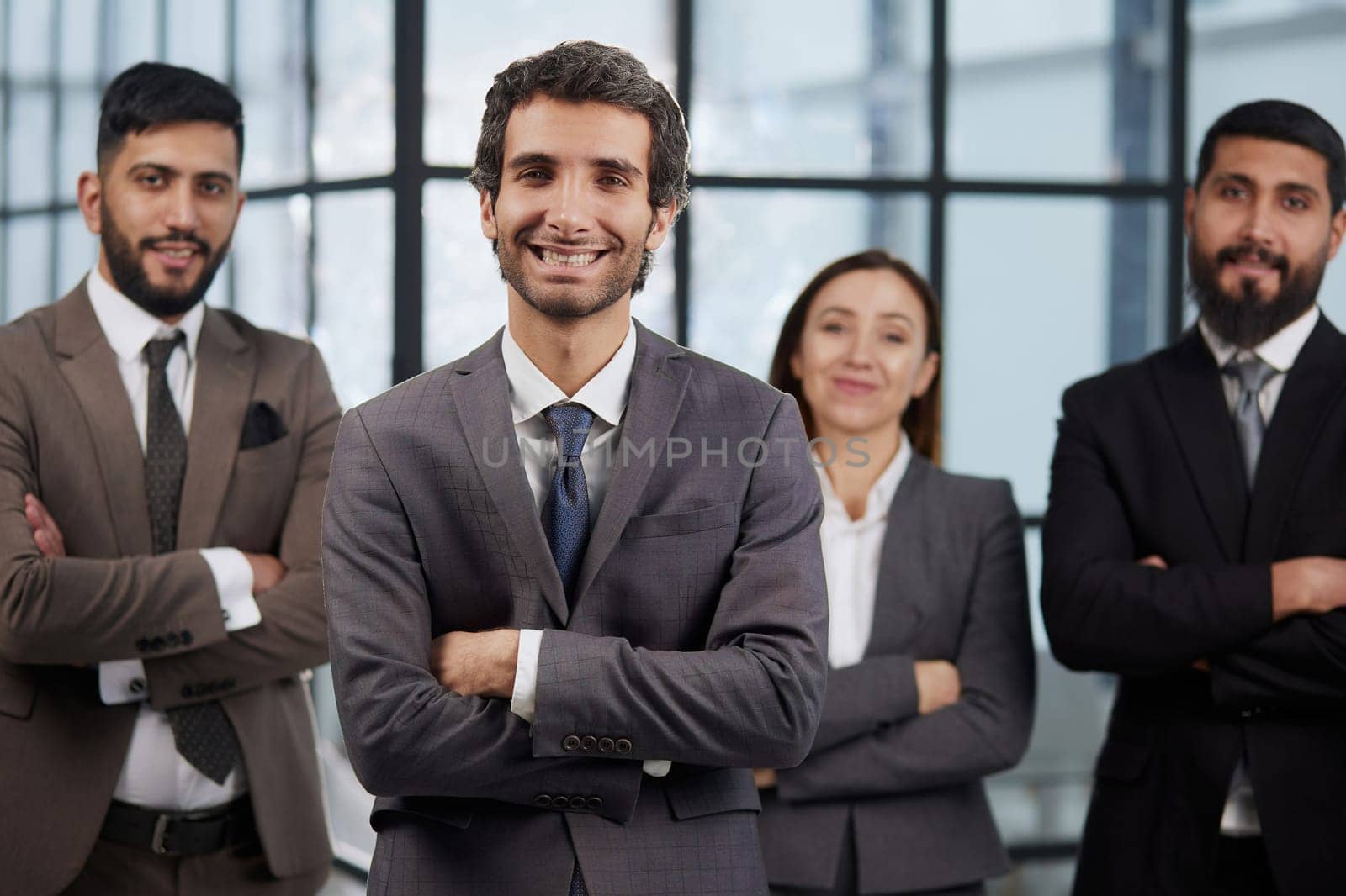 portrait shot of smiling business team of four standing and smiling at camera against a modern office background