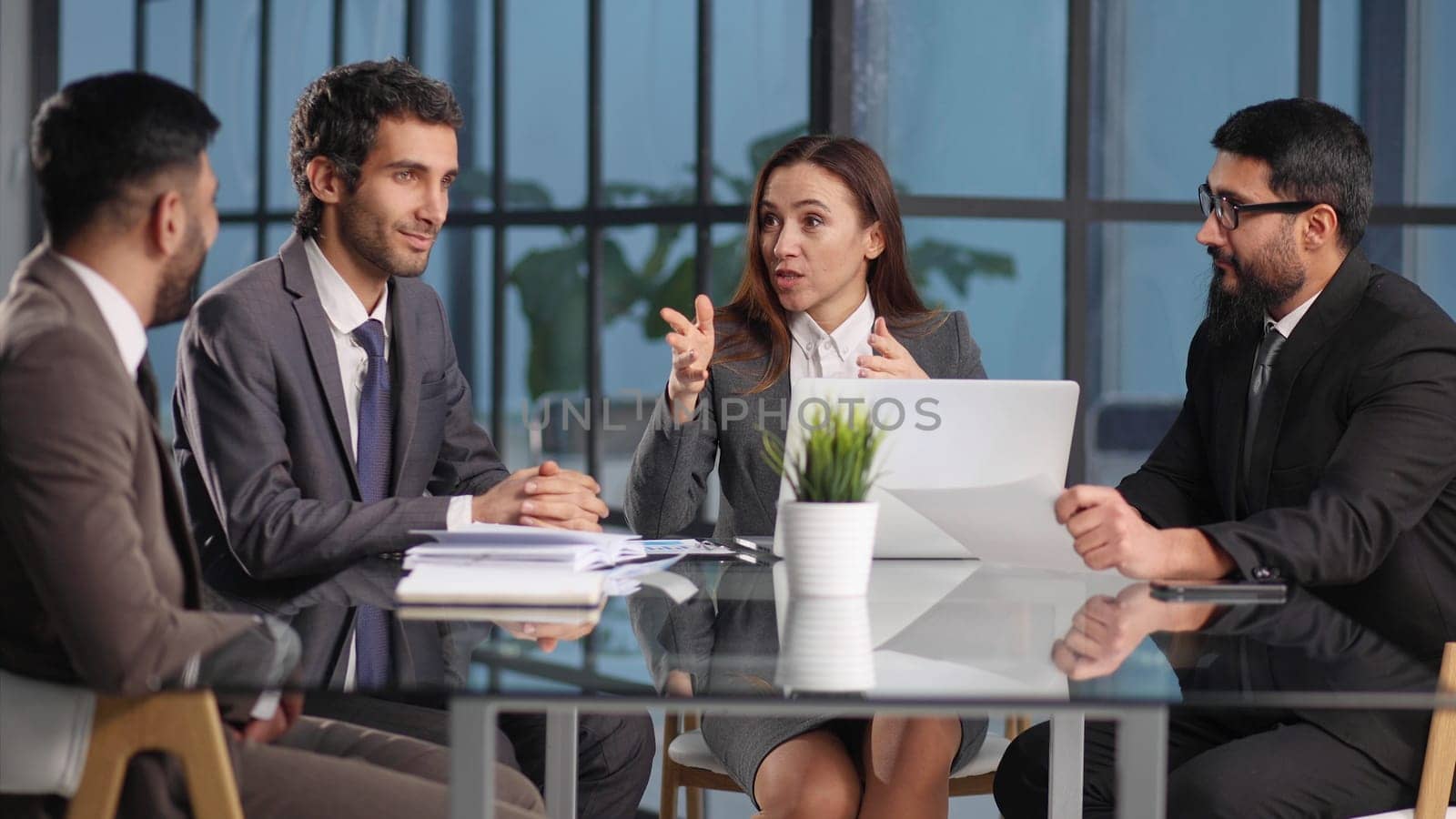 Joyful colleagues discussing project while sitting at table in office