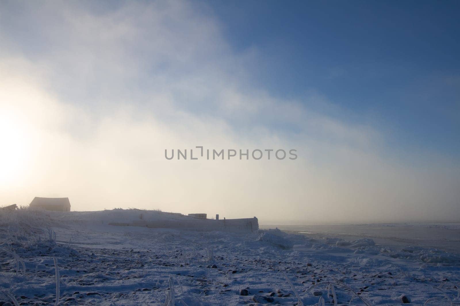 Cabin or building covered in snow with sun setting in the background near Churchill Manitoba