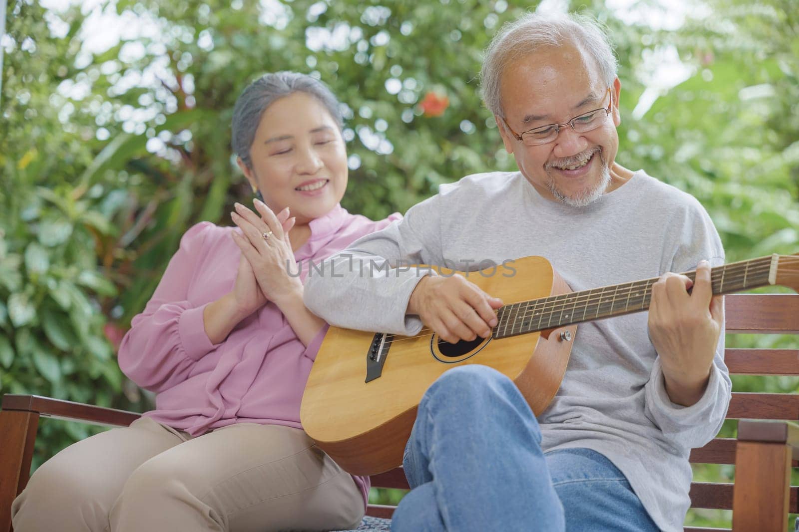 Asian senior couple elderly man playing guitar while his wife singing together outdoors at house, Activity family health care, Enjoying lifestyle during retirement life having fun of senior older