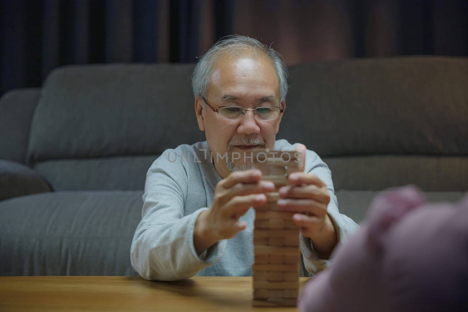 Happy grandparents Asian family enjoy playing toy block with little daughter and mother together at home night time, Smiling parent having fun play build constructor tower of wooden blocks, education