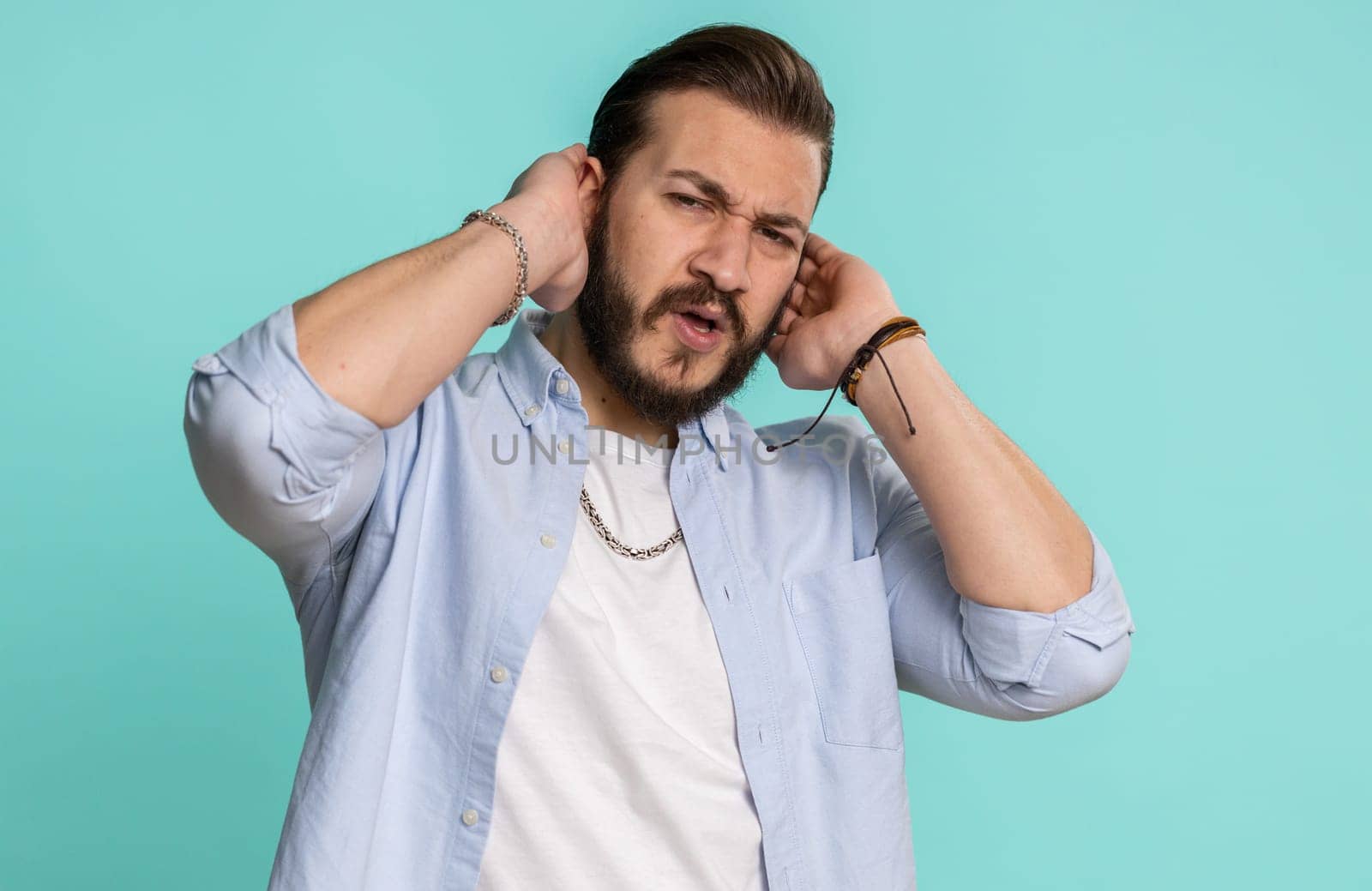 Dont want to hear and listen. Frustrated annoyed irritated lebanese man covering ears gesturing No, avoiding advice ignoring unpleasant noise loud voices. Handsome arabian guy alone on blue background