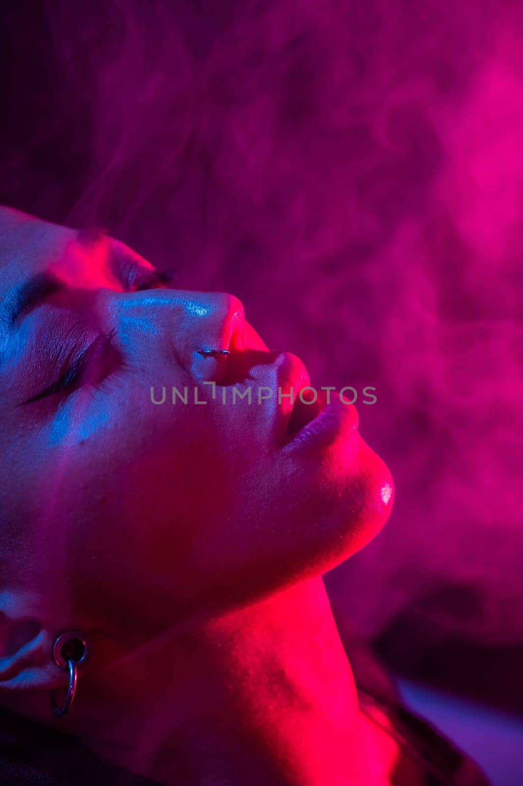 Asian woman with short haircut smoking in neon light. close-up portrait. by mrwed54