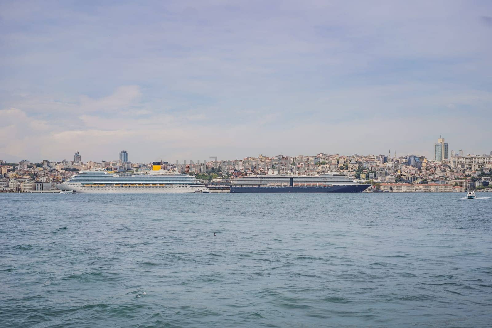 Huge cruise ship docked at terminal of Galataport, located along shore of Bosphorus strait, in Karakoy neighbourhood, with Galata tower in the background.