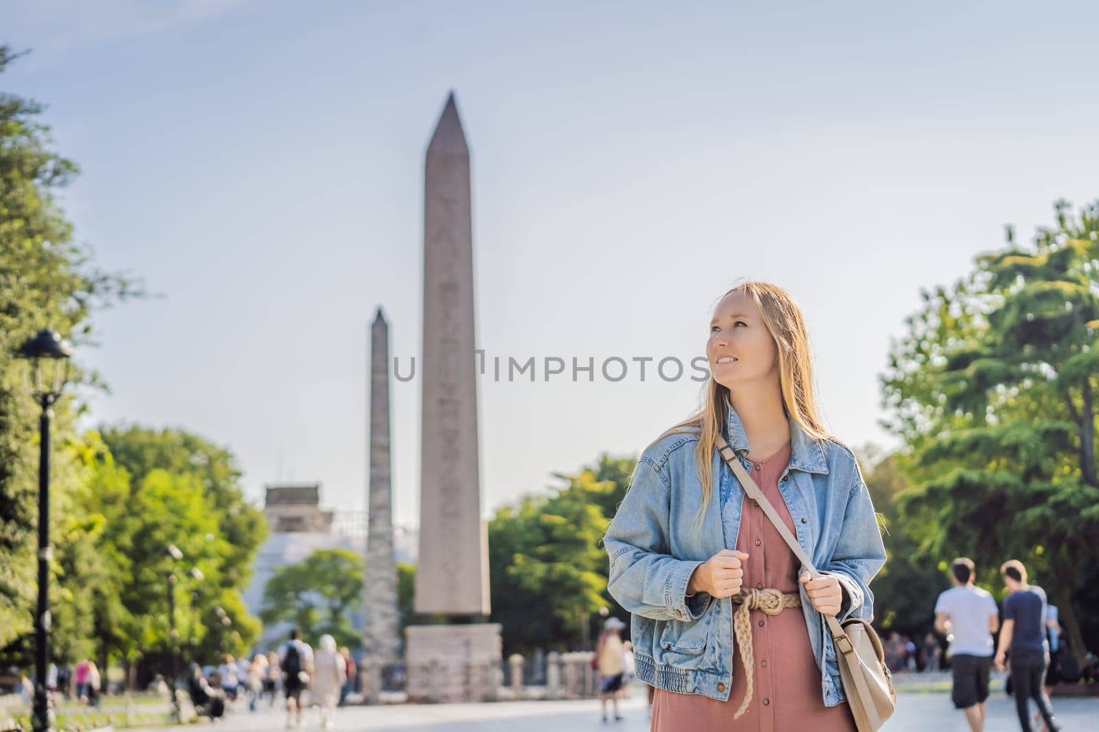Woman Tourist in Istanbul against the background of Obelisk of Theodosius is the Ancient Egyptian obelisk of Pharaoh Thutmose III places in the Hippodrome of Constantinople, Turkey. Theodosius Dikilitasi.