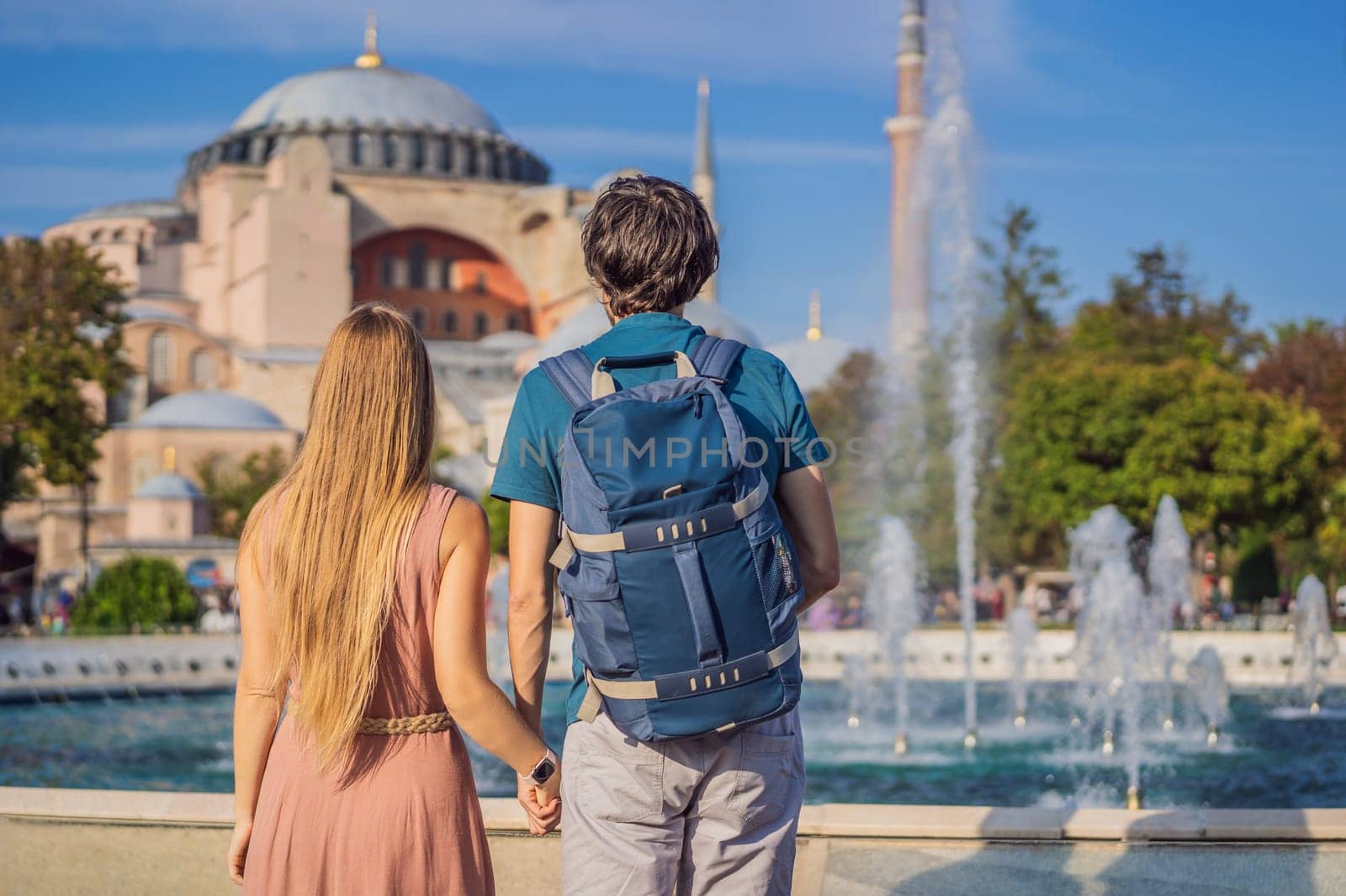 Happy couple of tourists in the honeymoon in Istanbul enjoy beautiful view on Hagia Sophia Cathedral, famous islamic Landmark mosque, Travel to Istanbul, Turkey. Sunny day architecture and Hagia Sophia Museum, in Eminonu, istanbul, Turkey. Turkiye.
