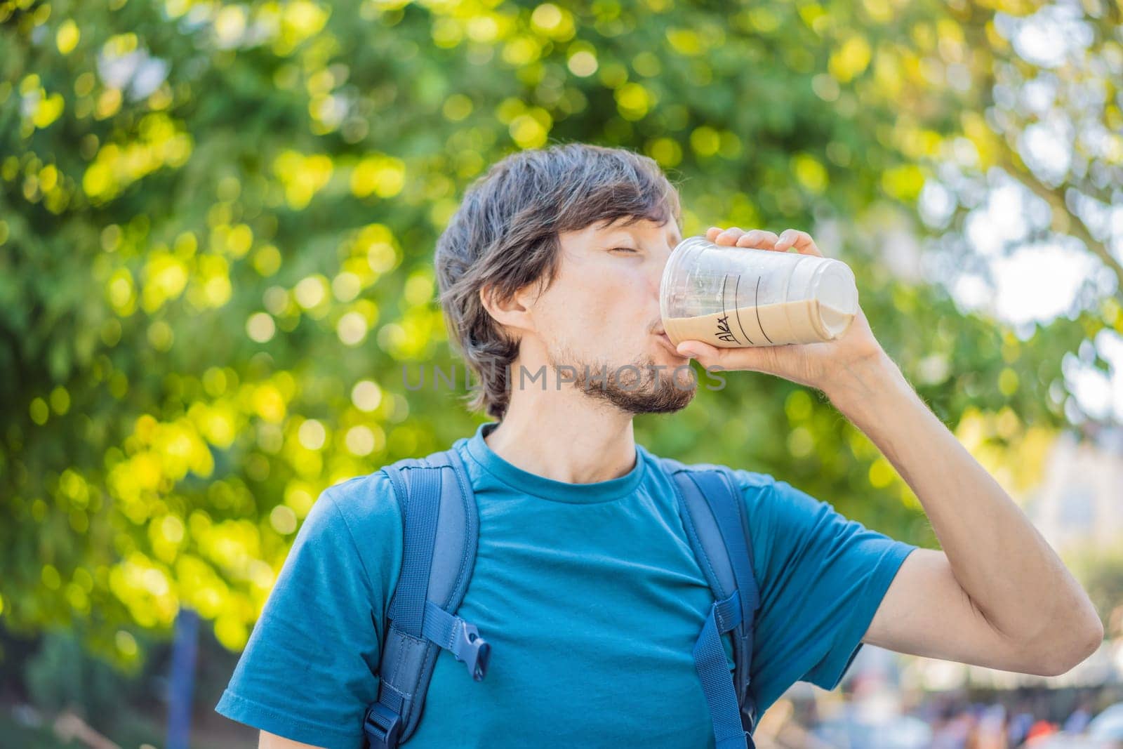 Man holding an iced coffee in a plastic to-go cup.