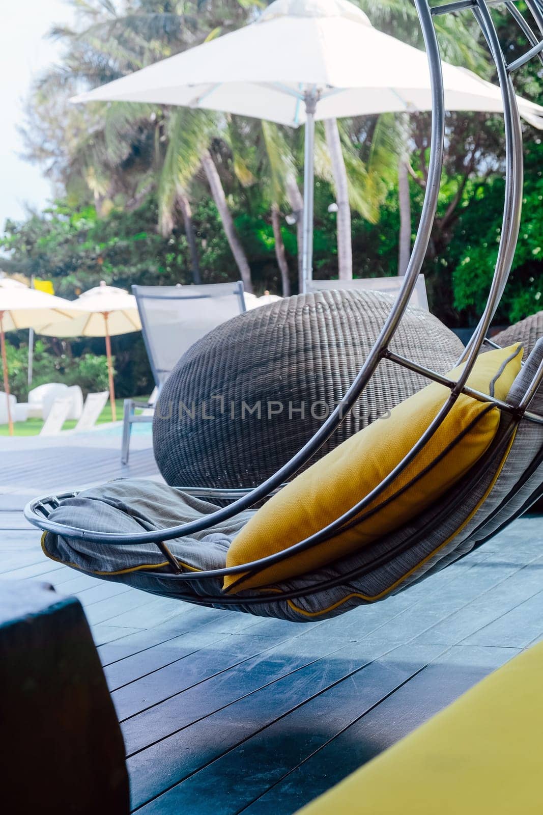 Image of Relaxing chairs with pillows beside swimming pool